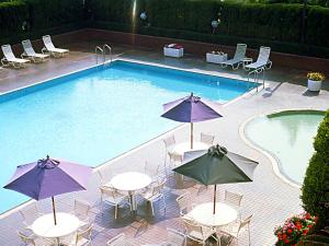 鹿儿岛Art Hotel Kagoshima的旁边设有桌子和遮阳伞的游泳池