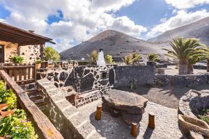 UgaCasa Rural Vega de Timanfaya的石头庭院设有桌子和山脉