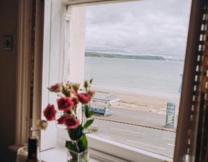 韦茅斯Pebble View - Central Cosy with Sea-Views的花瓶坐在窗户上,享有海滩美景