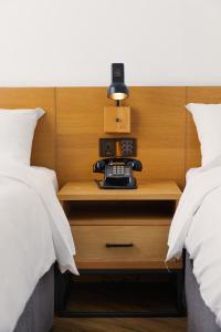 台中市新蓝天旅栈的一张睡床,床之间有床头柜上的电话