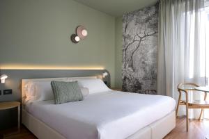 卢卡Hotel Ilaria的卧室配有白色的床和桌子