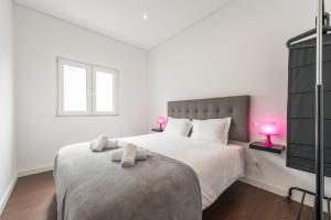 加亚新城GuestReady - Spacious modern stay in Porto的白色卧室配有一张带两个粉色灯的大床