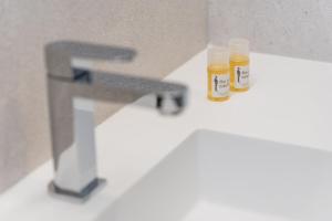 波尔图GuestReady - Modern luxe getaway in Vitória的浴室水槽内放两瓶蜂蜜