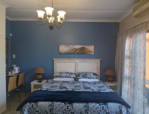 布隆方丹SONHOS dreams Self catering apartment Unit 1的一间卧室配有一张带蓝色墙壁和吊灯的床。