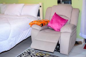 KakamegaUpper Haven Apartment的一间卧室配有一张床、一把椅子和枕头