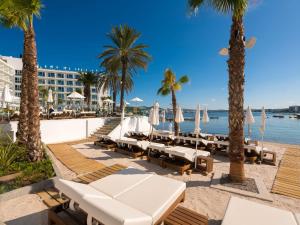 圣安东尼奥湾Amàre Beach Hotel Ibiza - Adults Recommended的海滩上,有椅子,棕榈树,酒店