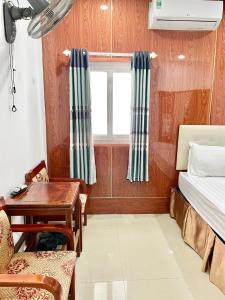 顺化Ngọc Lan Homestay的客房设有书桌、床和窗户。