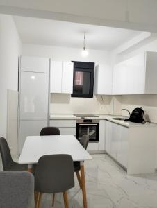 蒂瓦特Tivat Apartman的白色的厨房配有白色的桌子和椅子