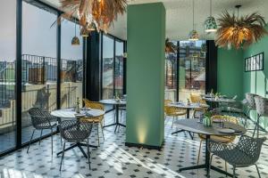波尔图Vincci Bonjardim的餐厅设有桌椅和大窗户。
