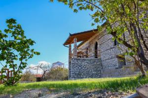 培拉特Villa Shpiragu Village Experience的一座位于山上的石头建筑,设有阳台