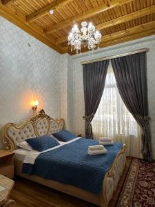 撒马尔罕Zilol Baxt Hotel的一间卧室配有一张带蓝色床单和吊灯的床。