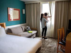 Courcouronnes诺沃特艾弗里库尔库洛纳酒店的一位抱着孩子的女人,看着酒店房间的窗户