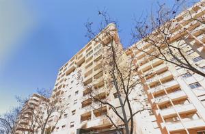 萨拉戈萨Apartamentos El Pilar Suites 3000的前面有一棵树的高楼