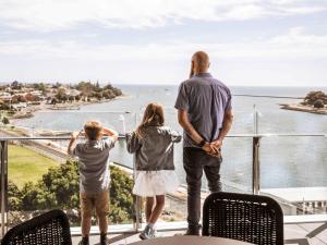 德文港Novotel Devonport的男人和两个孩子站在一个海景阳台上