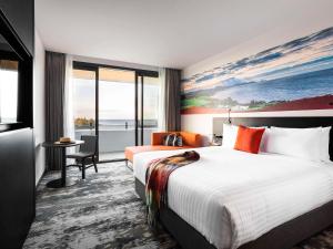 德文港Novotel Devonport的酒店客房设有一张大床和一张书桌。