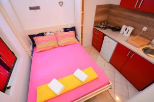 科托尔Majka 2 Apartments的一间小房间,厨房内配有一张粉红色的床