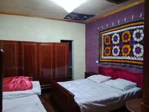 撒马尔罕Hostel Gulsara的卧室设有两张床,墙上挂有挂毯