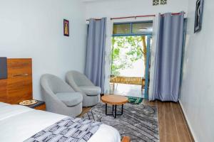 鲁亨盖里Ruhondo Beach Resort的一间卧室配有一张床、两把椅子和一个窗户