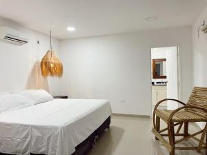 圣玛尔塔Hermosa habitación en casa campestre con piscina cerca al aeropuerto的一间卧室配有一张床、一把椅子和一个吊灯。