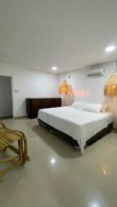 圣玛尔塔Hermosa habitación en casa campestre con piscina cerca al aeropuerto的一间卧室配有一张大床和两个吊灯。