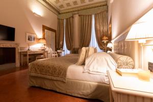 佛罗伦萨奎恰尔迪尼宫殿酒店的一间卧室配有一张大床、一张桌子和一张书桌