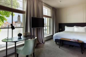 迪温特Pillows Luxury Boutique Hotel aan de IJssel的酒店客房设有一张床、一张书桌和窗户。
