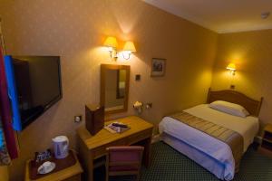 伯恩茅斯The Trouville Bournemouth的酒店客房配有一张床、一张书桌和一台电视。