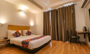 新德里Hotel Majestic stay - East of Kailash的酒店客房配有一张床、一张桌子和一把椅子。
