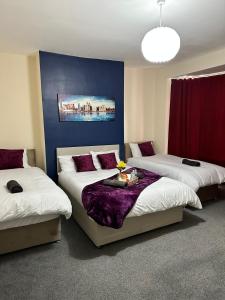 利物浦Elm Vale Lodge的一间设有三张床和蓝色墙壁的房间