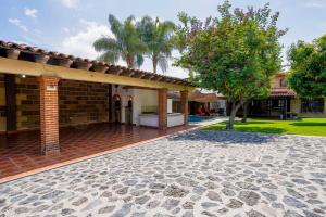 瓦兹特佩克Amazing family house in Oaxtepec Pool & Hot tub的砖屋,带有庭院和树
