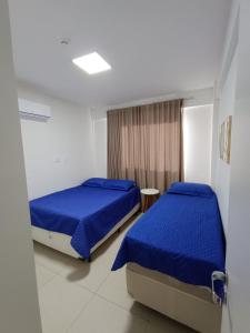 瓜拉久巴Lindo flat, na beira do lago, na melhor praia da Bahia的配有蓝色床单的客房内的两张床