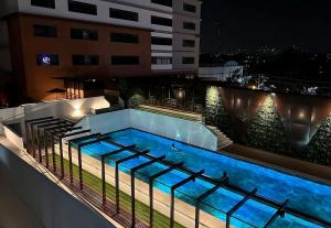 危地马拉Apartamento en centro Ciudad de Guatemala z12的一座游泳池,在晚上在一座建筑的顶部