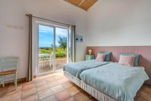 西尔韦斯Quinta das Piteiras Turismo Rural的一间卧室设有一张床和一个滑动玻璃门
