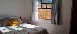 库尼亚Chalé na Montanha的一张带黄色枕头和窗户的床