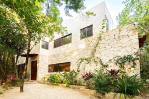 艾库玛尔* Dream Villa on Private Cenote 10min to Beach的一座石墙和树木的房子