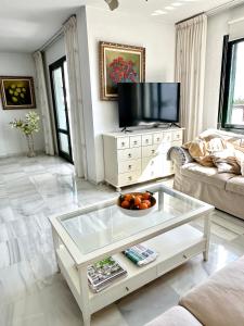 贝纳尔马德纳Penthouse Benalmadena Arroyo de la Miel centro的客厅配有玻璃咖啡桌和电视