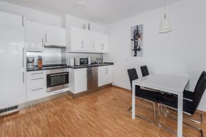 柏林Apartment Isabella的厨房配有白色橱柜和桌椅