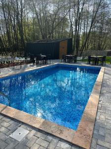 斯科普里Hotel Blisku do gradot的大型蓝色游泳池设有桌子