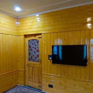 古尔马尔格The Himalayan Inn homestay的挂在木墙上的平面电视