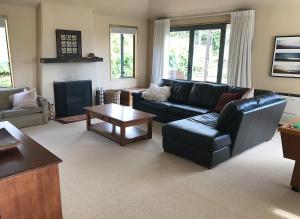 瓦纳卡Sargood Splendour - Wanaka Holiday Home的客厅配有黑色真皮沙发和桌子