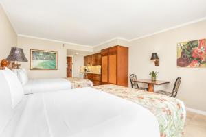 檀香山Luana Waikiki Hotel & Suites的白色卧室配有两张床和一张桌子