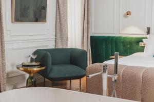 波尔多Hôtel Singulier Bordeaux的酒店客房带绿椅和一张床