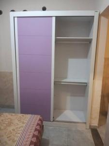 马卡埃Residencial Barbosa - Apto 102的一个带紫色门和书架的空衣柜