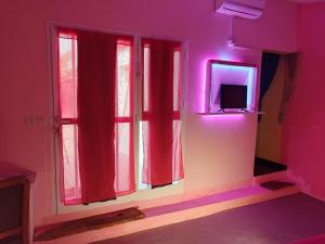 NdanganeLa Maison Blanche的客房设有带红色窗帘的窗户和电视。