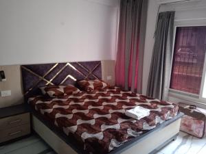 勒克瑙Ishita villa的一间卧室配有一张带床罩的床和窗户