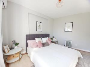 阿尔布费拉Feliz Algarve的白色卧室配有带粉红色枕头的大床