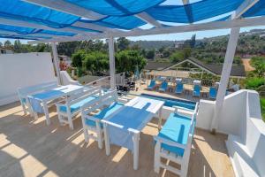 GelemişSisyphos Hotel的一个带蓝色桌椅的庭院和一个游泳池