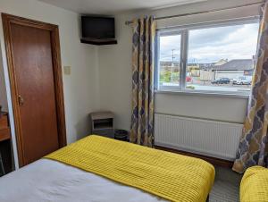 班多伦Fairy Bridge Lodge的一间卧室配有一张带黄色毯子和窗户的床