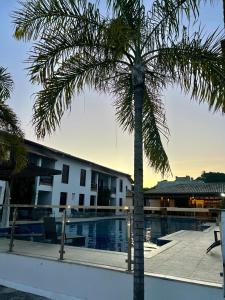 塞古罗港Encantos de Itaperapuã的一座带游泳池的建筑前的棕榈树