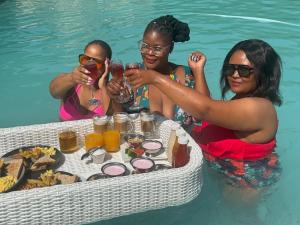 伯诺尼Africa Paradise - OR Tambo Airport Boutique Hotel的三名妇女在游泳池喝葡萄酒